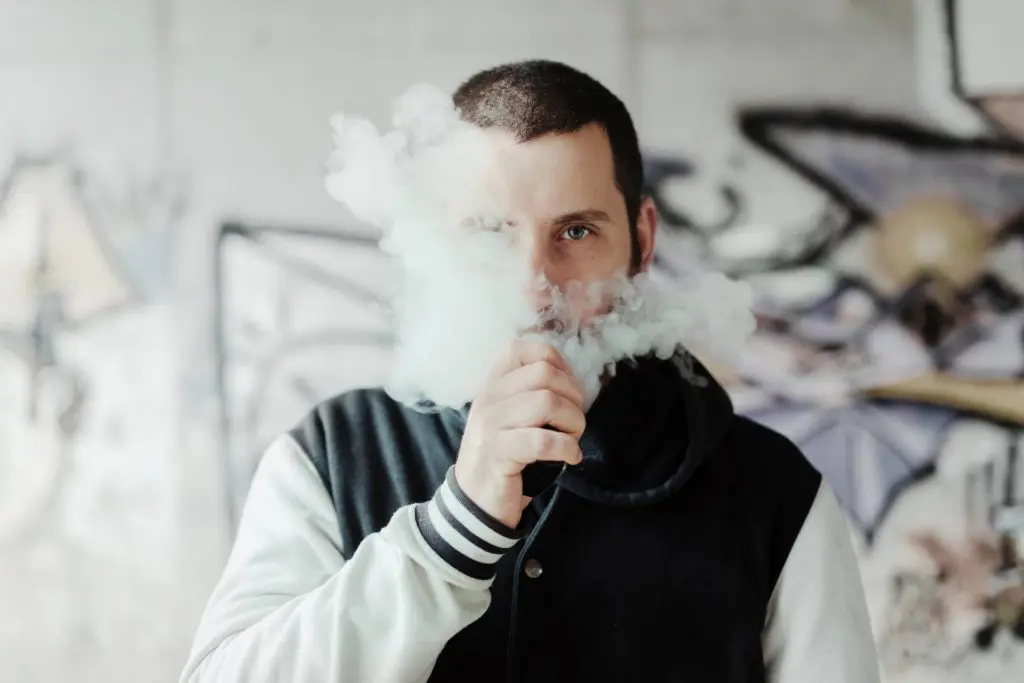 Junger Mann zieht an einer E-Zigarette